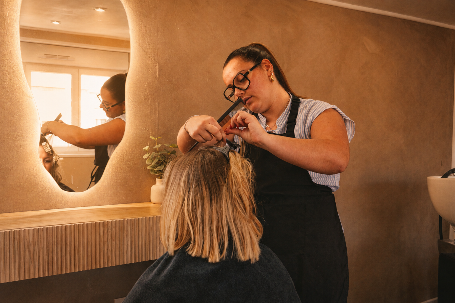 Close-up of a hairstylist styling hair with a brush and dryer in a salon setting.